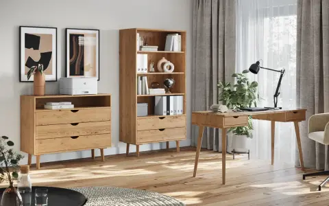 Jasny, drewniany kolor mebli tworzy przytulną atmosferę w domowym biurze. Komoda, regał i biurko wykonane z tego materiału idealnie komponują się z jasnym wnętrzem.