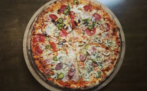 Pizza 32 cm z różnymi dodatkami: salami, kukurydza, jalapeno, pieczarki, ogórek, szynka.