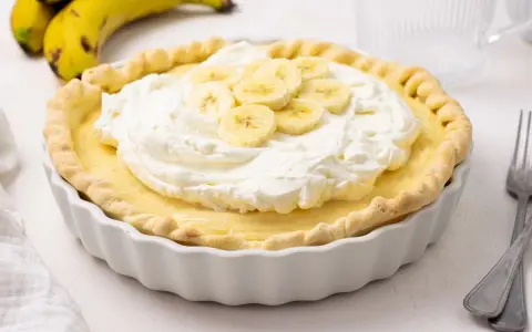 Deliciosa tarta de plátano con crema batida y rodajas de plátano fresco.