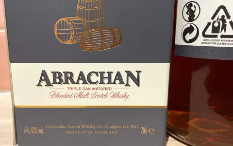 Elegancka butelka Abrachan Blended Malt Scotch Whisky, potrójnie dojrzewająca w dębie, z beczkami na etykiecie.