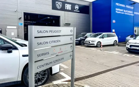 Znak kierunkowskazów w ASO wskazuje salon Peugeot, salon Citroën, serwis i centrum szkoleń.