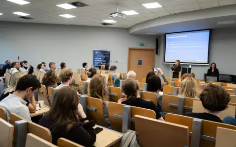Wykład o specjalizacji BI, gdzie można zdobyć wiedzę potrzebną do zrobienia magisterki w rok. Studenci słuchają prezentacji.