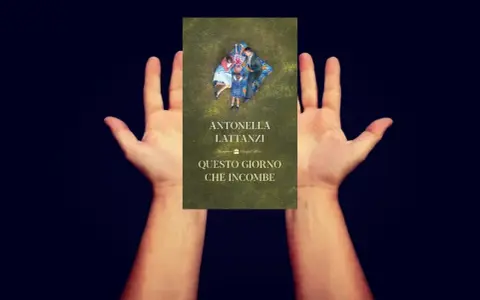 Mani aperte sorreggono la copertina del libro "Questo giorno che incombe", con una famiglia distesa sull'erba.