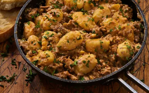 Herzhafte Gnocchi Pfanne mit Hackfleisch und Petersilie, serviert in einer Gusseisenpfanne. Dazu geröstetes Brot.