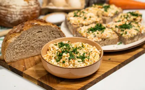 Pyszna pasta na kanapki z jajek, warzyw i ziół, podana z chlebem. Idealna na śniadanie lub przekąskę.