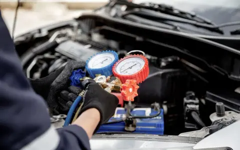 Mechanic checks car AC pressure with gauges. This helps determine how much to fix AC in car.