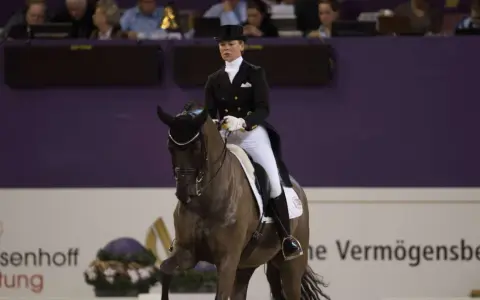 Kira Wulferding im Dressurstall, elegant in Frack und Zylinder, präsentiert ihr Pferd in einer anspruchsvollen Lektion.
