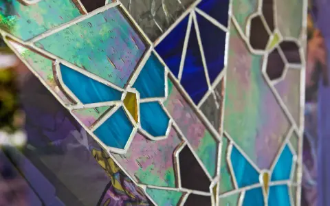 Un vitrail sur mesure aux couleurs vives, avec des motifs de papillons bleus et des éclats irisés.