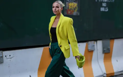 Kobieta w żółtej marynarce i zielonych spodniach, z limonkową torebką. Jej stylizacja to prawdziwe koło kolorów ubrania, łączące energię i elegancję.