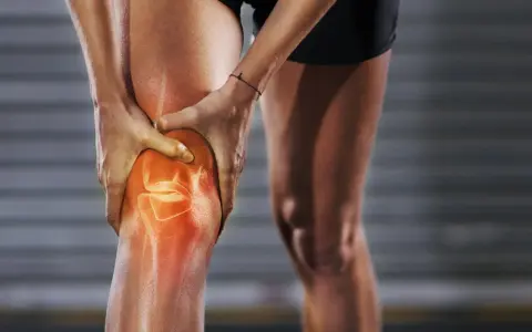 Person hält schmerzendes, dickes Knie. Was tun bei Knieproblemen? Rote Hitze zeigt Entzündung.