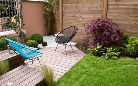 Aménagement d'un petit jardin de 100m2 : terrasse en bois, mobilier design, gazon et végétation luxuriante pour un espace détente moderne.