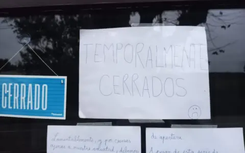 Cartel de "CERRADO" y otro escrito "TEMPORALMENTE CERRADOS" en la ventana de un bar restaurante.