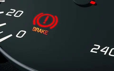 The car's dashboard shows the red brake light on, indicating a potential issue.