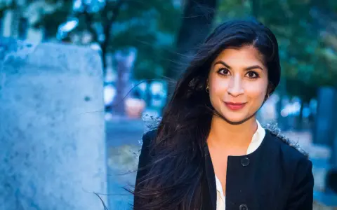 Soraya Hashim ler mot kameran, hennes mörka hår blåser i vinden.