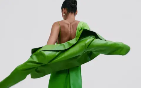 Mujer con un vestido verde brillante y una chaqueta verde vibrante. Un look audaz para combinar vestido verde con chaqueta.