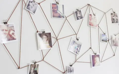 Sznurek tworzy geometryczny wzór na ścianie, na którym wiszą zdjęcia. Różnorodne tematy fotografii, od dzieci po krajobrazy, tworzą osobistą galerię.