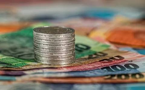 Stos monet na kolorowych banknotach. Czy to symbol najlepiej płatnych zawodów w Norwegii?