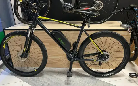 Czarny rower z żółtymi akcentami, wyposażony w baterię i silnik, prezentuje tani zestaw do konwersji roweru na elektryczny.
