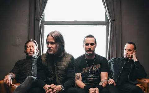 Alter Bridge Sverige: bandmedlemmar sitter på en soffa framför ett fönster.