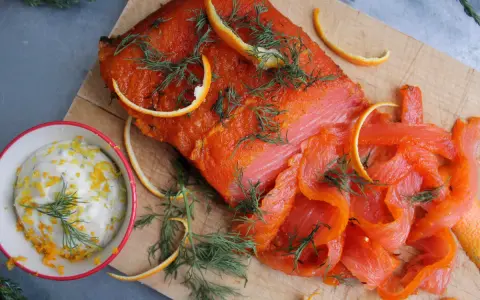 Rökt lax med apelsinzest och dill, serverad med en krämig sås till lax. Perfekt för en festlig måltid.