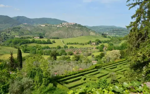 Un labirinto verdeggiante si apre su dolci colline e borghi arroccati nei Monti Sabini, un paesaggio idilliaco sotto un cielo azzurro.