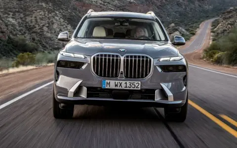Szary BMW X7M pędzi krętą drogą przez pustynny krajobraz.