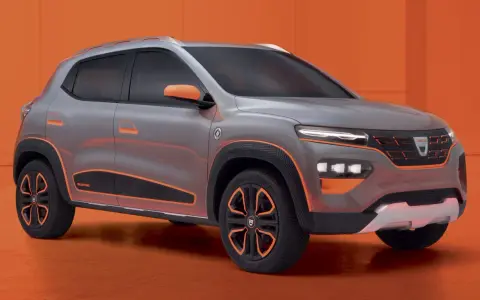 Szary samochód Dacia Spring z pomarańczowymi akcentami na tle pomarańczowym.