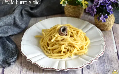 Un piatto di pasta burro e alici, condita con un tocco di sapore marino, servita su un piatto bianco decorato.