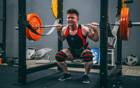 En person utför squats med vikt i ett gym.