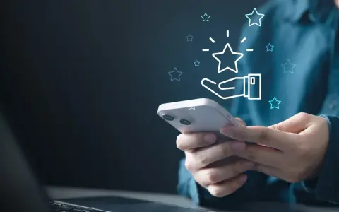 Dłoń trzyma smartfon, a nad nim świecą gwiazdki. To wizualizacja tego, czym jest cashback – zwrot części pieniędzy za zakupy.