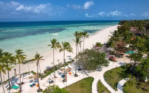Plaża na Zanzibarze z palmami, turkusową wodą i łodziami.