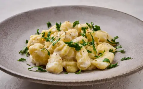 Pyszne gnocchi z kremowym sosem, posypane świeżą natką pietruszki. Idealne danie dla każdego miłośnika włoskiej kuchni.