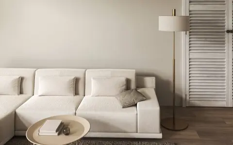 Divano modulare color tortora, tavolino ovale con libri, lampada da terra dorata e porta a soffietto in legno.