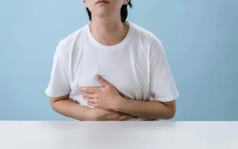 Persona con le mani sull'addome, che esprime disagio per nausea e giramenti di testa dopo allenamento.