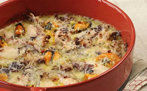 Un délicieux gratin de poisson et fruits de mer, gratiné au fromage, dans un plat rouge.