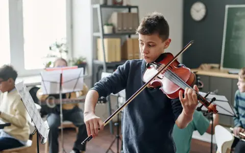 Chłopiec gra na skrzypcach, otoczony innymi dziećmi ćwiczącymi muzykę. Wszyscy skupieni, panuje **cicho w muzyce**, czekając na wspólne wykonanie.