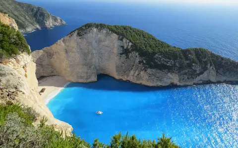 Grecja gdzie na wakacje? Zatoka Wraku na Zakynthos, z turkusową wodą i klifami, idealne miejsce na niezapomniany urlop.