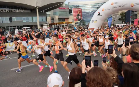 Uczestnicy maratonu w Warszawie, gotowi do startu. To świetny przykład, jak przygotować się do maratonu: trening, determinacja i wsparcie kibiców.