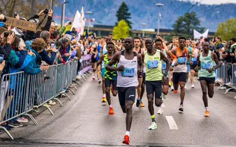 Läufer im Vordergrund einer Marathon-Geschichte, Zuschauer feuern sie an.