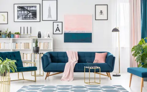 Granatowa sofa i fotele z pudrowym różem tworzą elegancką przestrzeń.