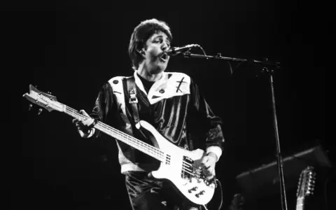 Paul McCartney, jeden z legendarnych amerykańscy piosenkarze lat 80., gra na gitarze basowej podczas koncertu.