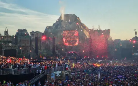 Tłum ludzi na największym festiwalu muzycznym na świecie, z wulkaniczną sceną i pokazem sztucznych ogni.