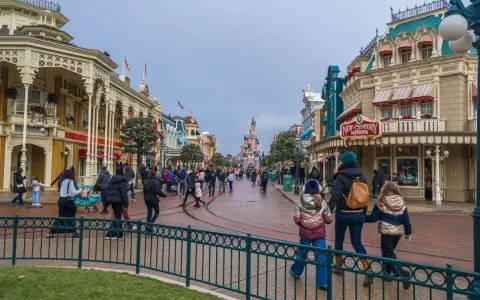 Menschen schlendern die Hauptstraße entlang, vorbei an Geschäften und dem Schloss. Ein Tag im Disneyland, vielleicht mit einem Disneyland Fastpass für die Attraktionen.