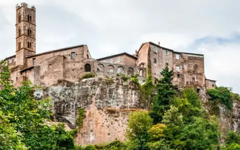 Un borgo medievale arroccato su una rupe, con un'alta torre campanaria. Un esempio dei borghi più belli del Lazio, immerso nel verde.