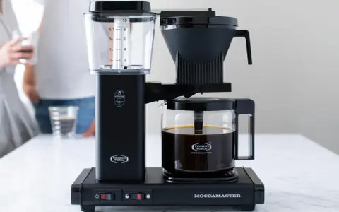 Elegancki, czarny ekspres przelewowy Technivorm Moccamaster z dzbankiem pełnym aromatycznej kawy. Idealny do porannego rytuału.