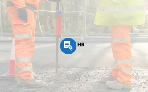 Prace interwencyjne na budowie. Pracownicy w pomarańczowych strojach i kamizelkach odblaskowych, symbol HR z banknotem 2 zł.