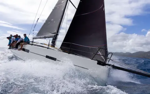 Équipage sur un voilier blanc, gery trentesaux, naviguant sur une mer agitée sous un ciel nuageux.