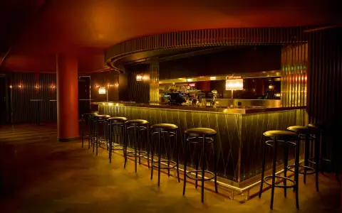 En elegant bar med gulddetaljer och barstolar, perfekt för en kväll på Rigoletto Stockholm.