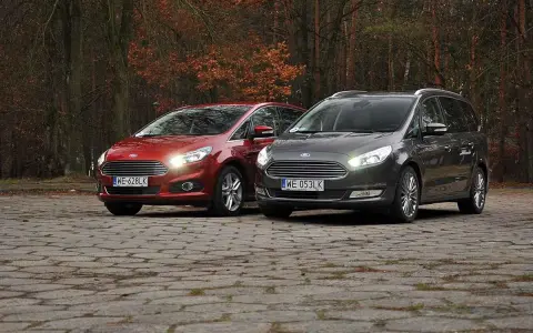 Dwa samochody Ford, czerwony S-Max i szary Galaxy, stoją na brukowanej nawierzchni w jesiennym lesie.
