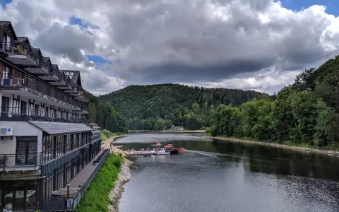 Hotel nad jeziorem Bystrzyckim, z plażą i pomostem, gdzie cumują łódki.